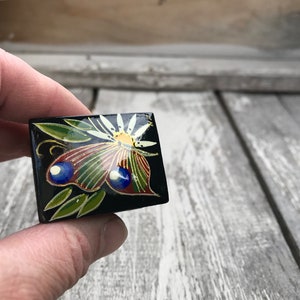 May include: A small black wooden box with a painted butterfly design. The butterfly has blue, green, red, and yellow accents.