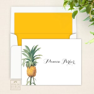 May include: A white card with a yellow envelope. The card has a pineapple illustration and the text "Monica Parker" in black cursive.