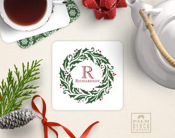 May include: A square white coaster featuring a green holly wreath illustration with red berries. In the center, a large red letter R is printed above the text RICHARDSON in a matching red serif font, creating a festive holiday design.