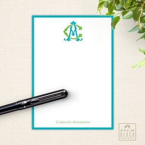 May include: A white notepad with a turquoise border and a green and turquoise monogram of the letters "CA" in a decorative font. The notepad has the text "Carolyn Anderson" printed at the bottom.