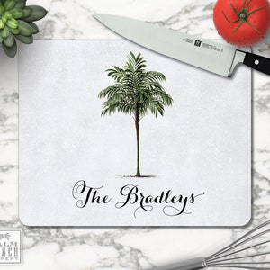 May include: White cutting board with a green palm tree illustration and the text "The Bradleys" in black cursive font.