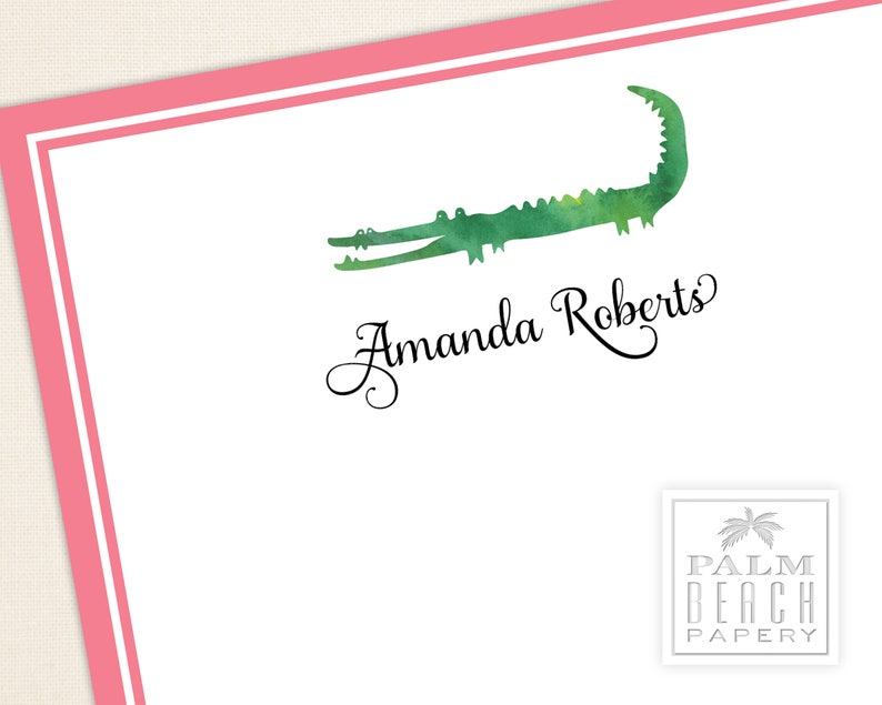 K&ouml;nnte beinhalten: Wei&szlig;es Briefpapier mit rosa Rand und einer Aquarell-Illustration eines Alligators. Der Name "Amanda Roberts" ist in eleganter Schrift geschrieben. Ein Logo von "Palm Beach Papery" befindet sich in der unteren rechten Ecke.