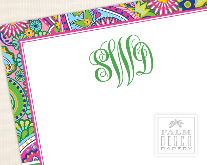 May include: A white card with a pink and green paisley border. The card has a green monogram "SJD" in the center and the text "PALM BEACH PAPERY" in the bottom right corner.