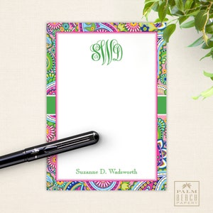 May include: A pink and green patterned notepad with a white writing area. The notepad has a green border and a pink stripe. The notepad has a monogram "SWD" in green at the top and the name "Suzanne D. Wadsworth" at the bottom.
