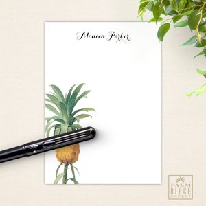 May include: White notepad with the name "Monica Parker" written in black cursive at the top. A pineapple illustration is in the bottom left corner. The notepad has a gold logo that says "Palm Beach Papery" in the bottom right corner.