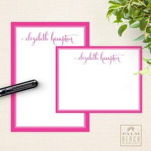 May include: Two white note cards with pink borders. The top card has the text "elizabeth hampton" in pink cursive writing. The bottom card has the same text in a smaller font size.