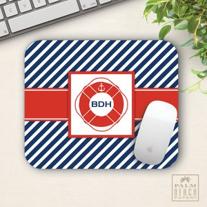 May include: A blue and red striped mouse pad with a red life preserver with an anchor and the initials "BDH" in white. The mouse pad is on a white surface.