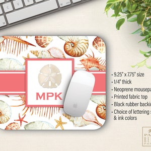 May include: A personalized mousepad with a seashell design. The mousepad is 9.25 inches by 7.75 inches and is 1/4 inch thick. The mousepad is made of neoprene with a printed fabric top and a black rubber backing. The mousepad features a pink and white color scheme with a seashell design and the initials "MPK" in black.