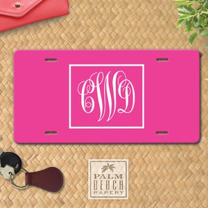 May include: A pink personalized license plate with a white monogram of the letters "CWD" in a decorative script font.