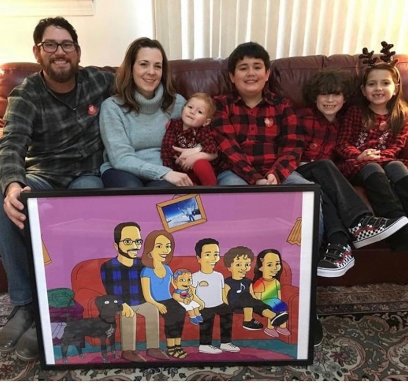 May include: A framed cartoon portrait of a family of seven, including a dog, sitting on a couch. The cartoon is drawn in a Simpsons-style, with yellow skin and exaggerated features. The portrait is set against a pink background.