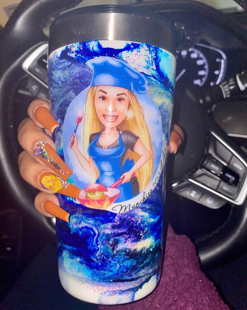 May include: A stainless steel tumbler with a blue, white, and purple marbled design. The tumbler features a cartoon illustration of a woman wearing a blue chef's hat and holding a spatula. The text "Munchies 2023" is printed on the tumbler.