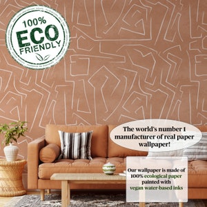 May include: A brown couch with a white and black striped throw pillow sits in front of a wall covered in a brown and white abstract wallpaper. The wallpaper has a 100% eco-friendly label. The text "The world's number 1 manufacturer of real paper wallpaper!" is written below the couch. The text "Our wallpaper is made of 100% ecological paper painted with vegan water-based inks" is written below the text about the wallpaper.