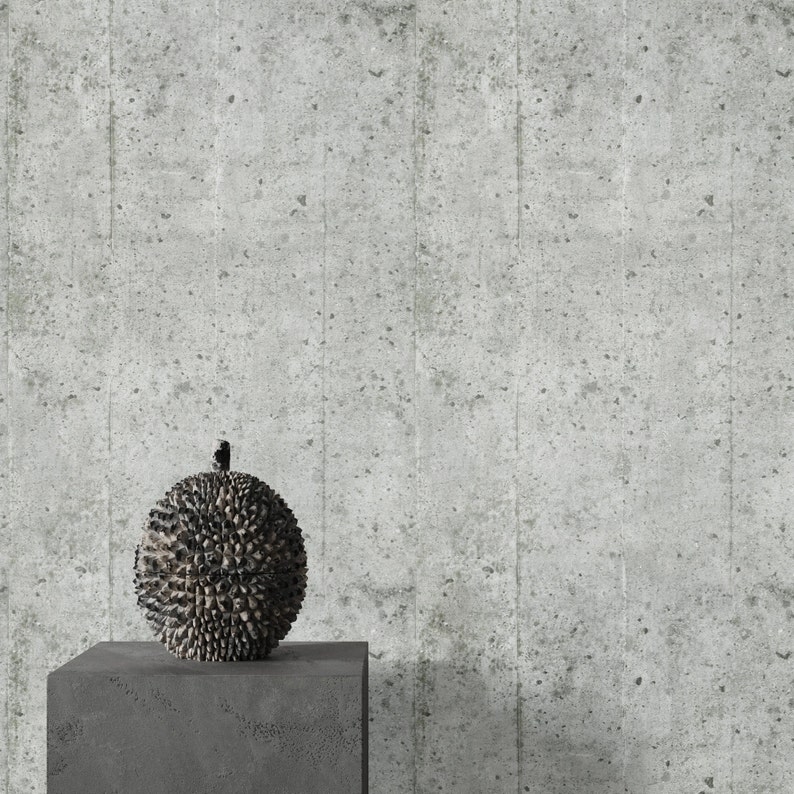 Puede incluir: Un objeto decorativo redondo y puntiagudo de color gris oscuro se encuentra sobre un pedestal de hormig&oacute;n gris frente a una pared de hormig&oacute;n gris.
