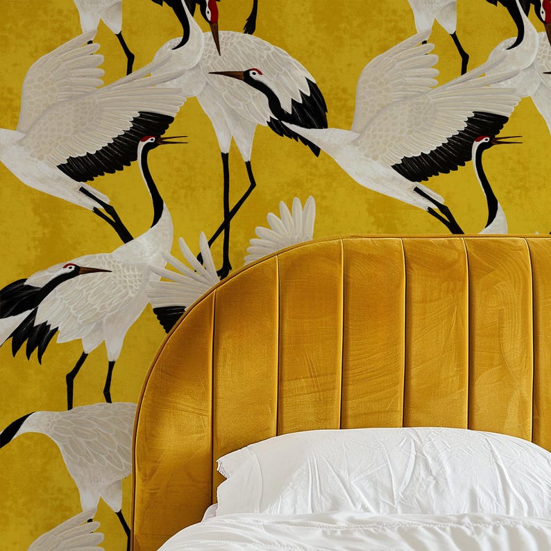 May include: A mustard yellow headboard with vertical channel tufting is paired with a white pillow and bedding. The background features a repeating pattern of white and black cranes on a yellow background.