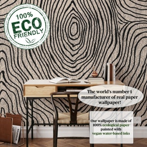May include: A room with a desk, chair, and wallpaper featuring a black and beige tree ring design. The wallpaper is labeled as 100% ecological paper with vegan water-based inks. The text says "The world's number 1 manufacturer of real paper wallpaper!"