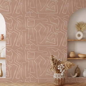 May include: A brown wall with a white abstract pattern. The wall is decorated with a woven basket filled with dried pampas grass and eucalyptus.