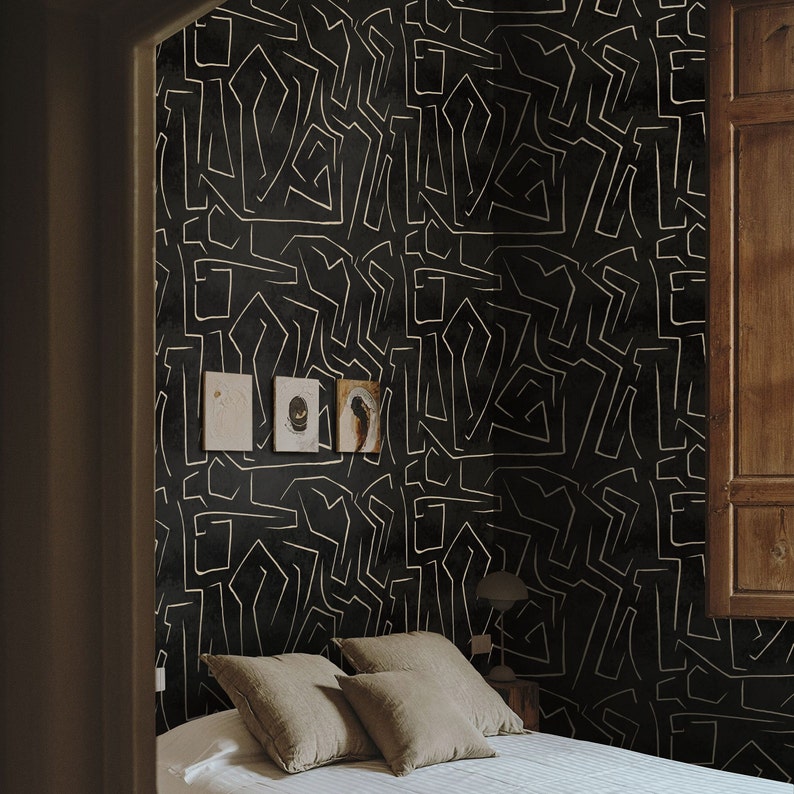 May include: A black and white patterned wallpaper with a white geometric design. A bed with a white duvet and brown linen pillows is in front of the wallpaper.
