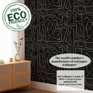 May include: Black and gold wallpaper with a geometric pattern. The text "100% ECO FRIENDLY" is in a green circle in the upper left corner. The text "The world's number 1 manufacturer of real paper wallpaper!" is in a white oval in the lower right corner. The text "Our wallpaper is made of 100% ecological paper painted with vegan water-based inks" is in a white rectangle in the lower right corner.