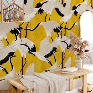 May include: A vibrant yellow wallpaper featuring a repeating pattern of white cranes with black wingtips and red accents. The birds are depicted in various poses against a textured background. The room is decorated with a bench, mirror, and framed artwork.