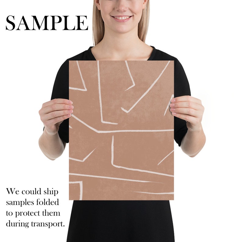 May include: A digital art print with an abstract design featuring white lines on a light brown background. The print is being held by a person.