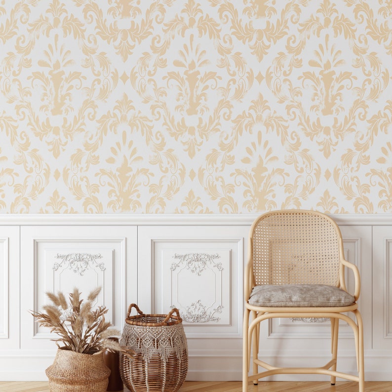 K&ouml;nnte beinhalten: Eine wei&szlig;e Wand mit einer beigefarbener Damastmuster-Tapete. Die Wand hat wei&szlig;e Wandvert&auml;felung mit einem dekorativen Design. Ein Korbstuhl mit einem beigefarbenen Kissen steht vor der Wand. Zwei Korbwaren mit gewebten Mustern stehen auf dem Boden vor dem Stuhl. Ein Strau&szlig; getrockneter Pampasgr&auml;ser befindet sich in einem Korb.