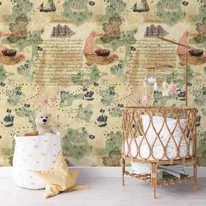 May include: A nursery room featuring wallpaper with a vintage treasure map print, a round rattan crib with white star-patterned bedding, a mobile with hanging stars, a white fabric storage bin with a teddy bear, and a yellow star-shaped pillow.