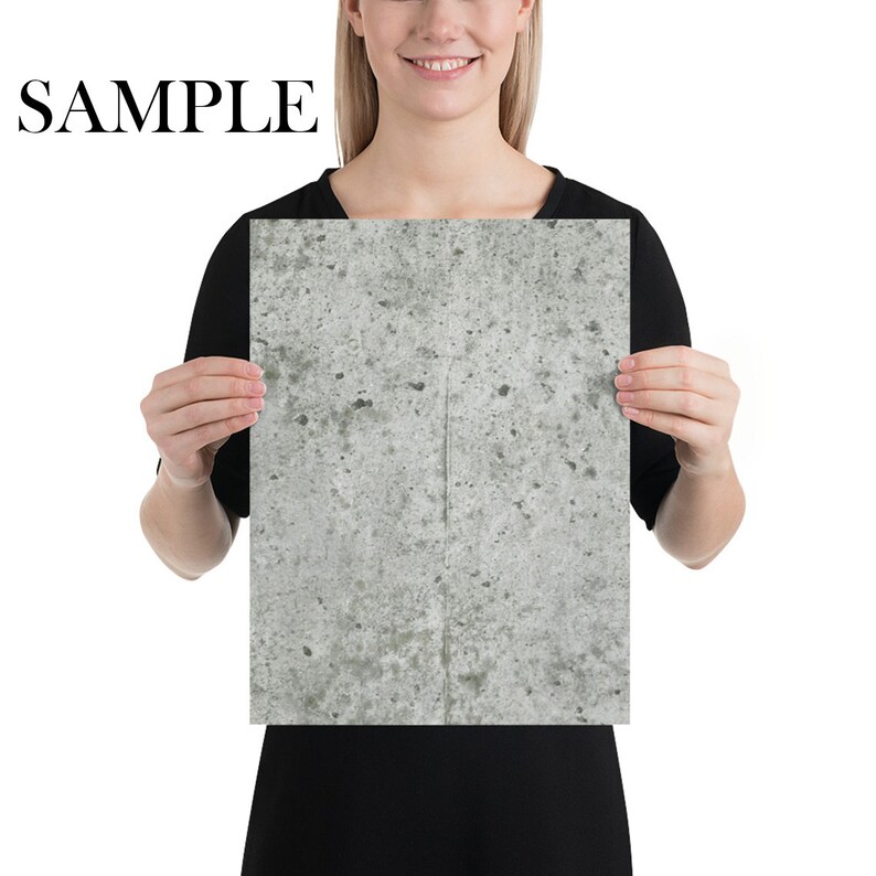 Puede incluir: Una persona sostiene un p&oacute;ster con una textura de hormig&oacute;n gris. El p&oacute;ster tiene un fondo gris claro con manchas y vetas grises m&aacute;s oscuras.