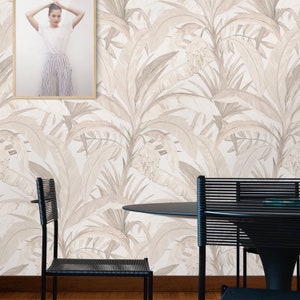 Pu&ograve; includere: Una sala da pranzo con carta da parati bianca con un motivo a foglie tropicali beige. In primo piano ci sono due sedie nere e un tavolo rotondo nero.