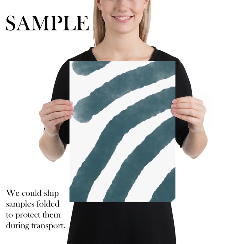 May include: A white and teal abstract art print with a series of curved lines. The print is being held by a person.