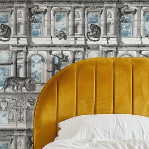 Op de afbeelding: Een mosterdgeel fluwelen hoofdbord met verticale kanaal tufting. De achtergrond is een zwart-wit behang met illustraties van apen, tijgers en architectonische elementen. Een wit kussen en beddengoed zijn zichtbaar.