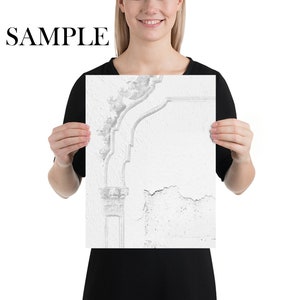 May include: A black and white photograph of a weathered, white wall with a decorative, ornate plaster molding. The molding is in the shape of a curved archway with intricate details.