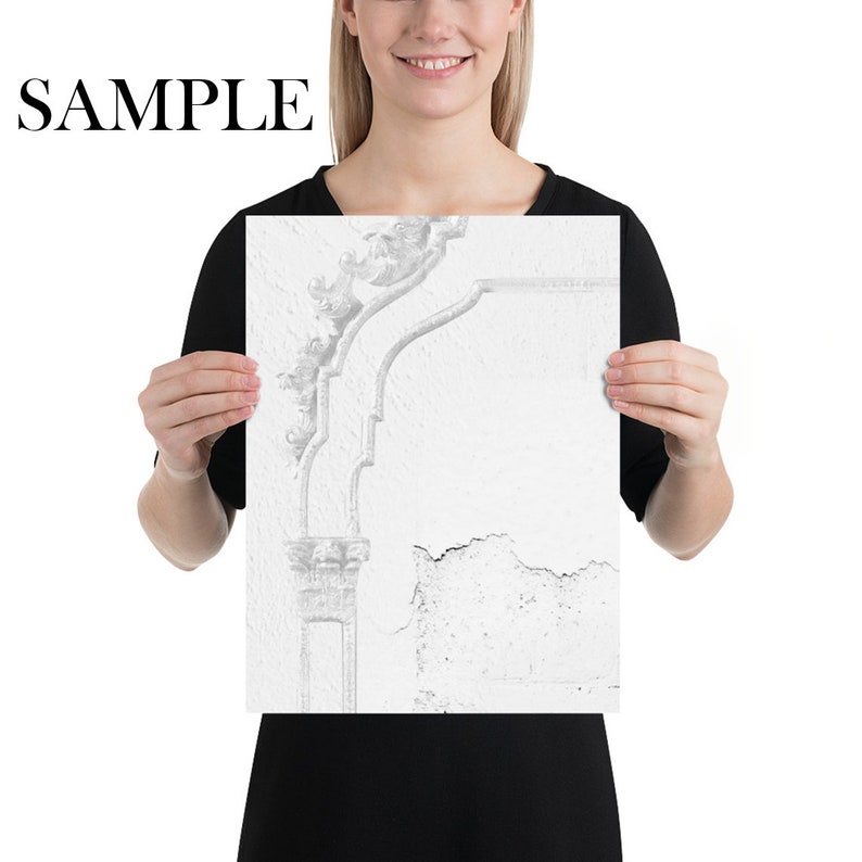 May include: A black and white photograph of a weathered, white wall with a decorative, ornate plaster molding. The molding is in the shape of a curved archway with intricate details.