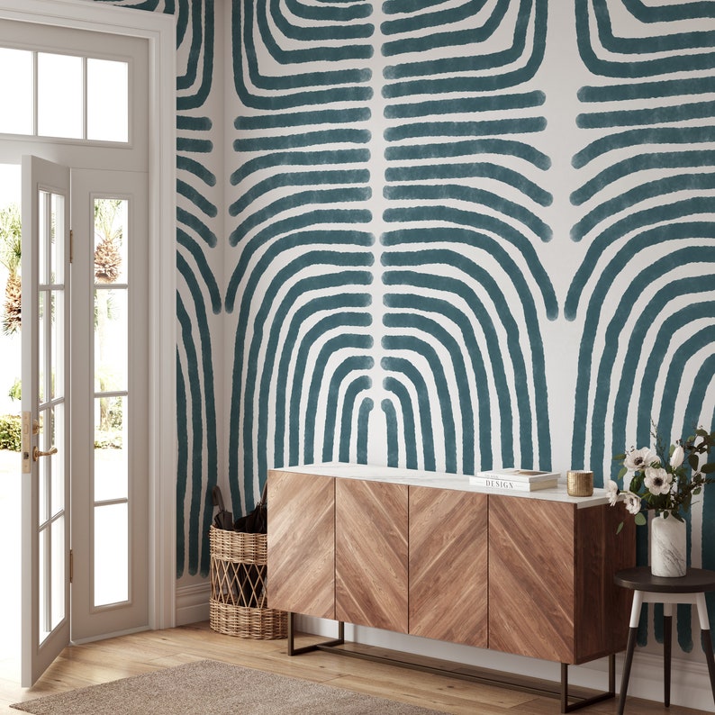May include: A wooden dresser with four drawers and a white marble top. The dresser is in front of a wall with a teal blue abstract pattern. The dresser has a chevron pattern on the front.