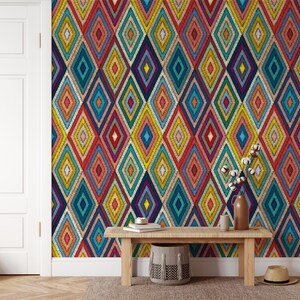 K&ouml;nnte beinhalten: Eine farbenfrohe geometrische Tapete mit einem Rautenmuster in Rot-, Blau-, Gelb-, Gr&uuml;n- und Oranget&ouml;nen. Die Tapete ist an einer Wand in einem Raum mit einer Holzbank und einem geflochtenen Korb angebracht.