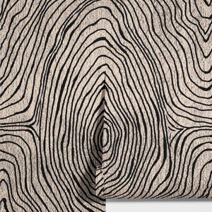May include: A close-up of a cream-colored fabric with a repeating pattern of black, curved lines resembling tree rings. The lines vary in thickness and create a textured, organic design. The fabric is partially rolled, revealing the pattern.