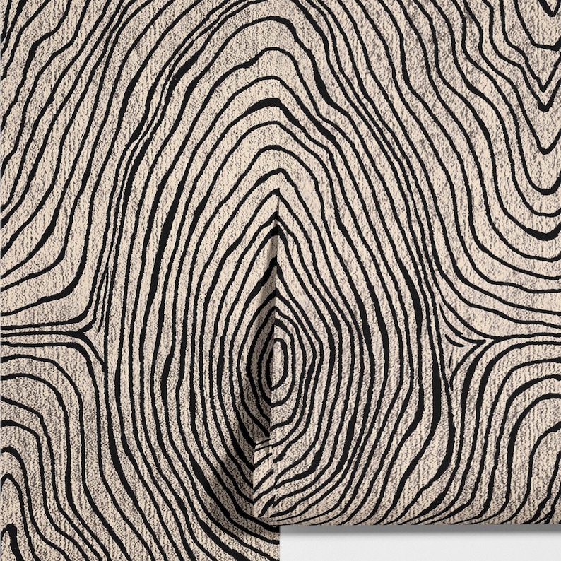 May include: A close-up of a cream-colored fabric with a repeating pattern of black, curved lines resembling tree rings. The lines vary in thickness and create a textured, organic design. The fabric is partially rolled, revealing the pattern.