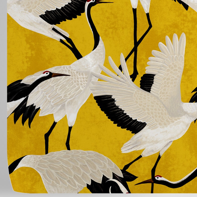 May include: A repeating pattern of white cranes with black wingtips and red markings on a mustard yellow background. The cranes are depicted in various poses, some with wings spread, others standing or in flight. The design has a textured, artistic appearance.