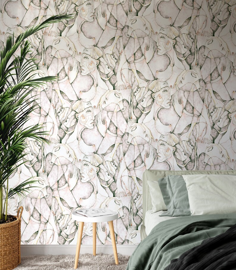 Puede incluir: Un papel tapiz blanco con un patr&oacute;n repetitivo de caras abstractas en tonos de rosa, verde y marr&oacute;n. El papel tapiz se muestra en un ambiente de dormitorio con una cama y una mesa peque&ntilde;a.