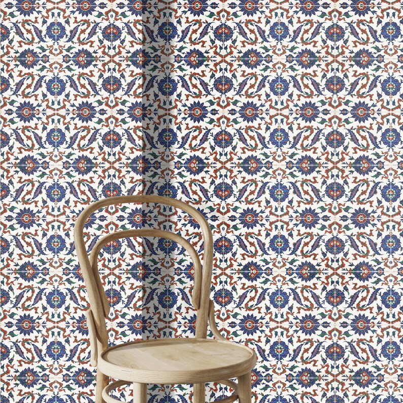 May include: A white chair with a wooden frame and a woven seat sits in front of a wall covered in blue, red, and green patterned tiles.