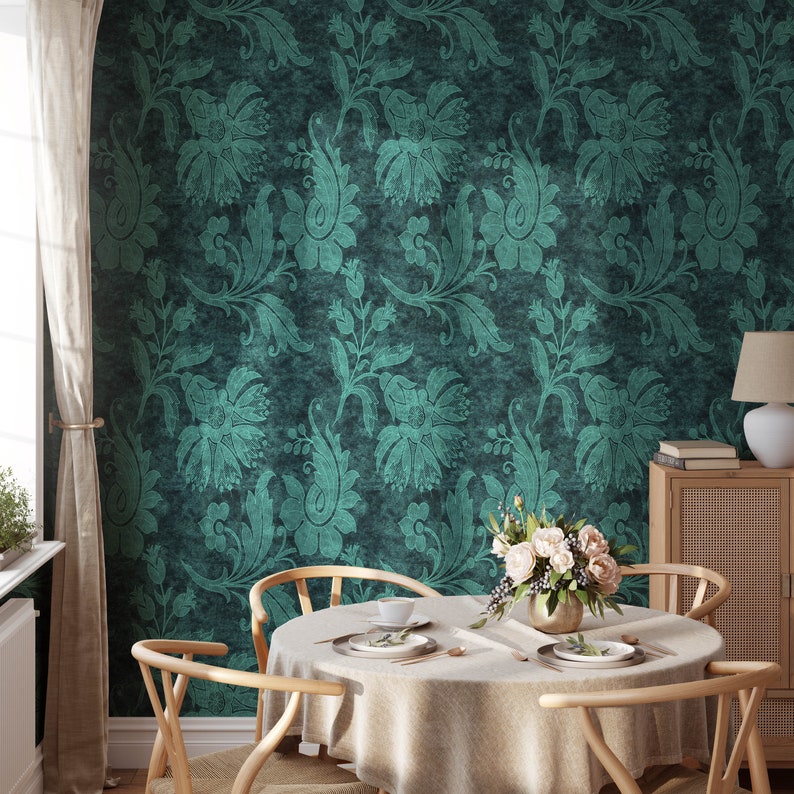 Pode incluir: Uma mesa de jantar com uma toalha de mesa branca, um vaso de flores brancas e duas cadeiras. A parede atr&aacute;s da mesa &eacute; coberta com papel de parede azul-esverdeado com um padr&atilde;o floral.