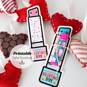 May include: Valentine's Day-themed printable lip balm holders and heart-shaped ornaments. The lip balm holders feature a lipstick design with the text "Happy Valentine's Day." The hearts are red, brown, and white.