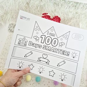 May include: Black and white printable crown with the text "I am 100 Days Smarter!" and illustrations of stars, hearts, lightbulbs, and pencils. The crown is designed for coloring and celebrating a milestone.