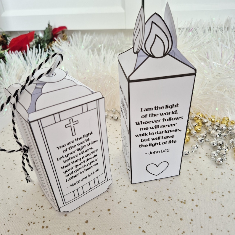 May include: Two white paper lanterns with black outlines and text. One lantern has a cross and the text "You are the light of the world." The other lantern has a flame design and the text "I am the light of the world." Both have Bible verses.
