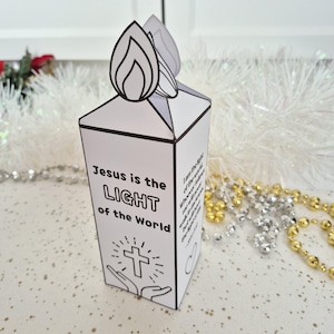 May include: A white paper candle-shaped box with the text "Jesus is the LIGHT of the World" and a cross graphic. The top features a flame design. Religious-themed craft.