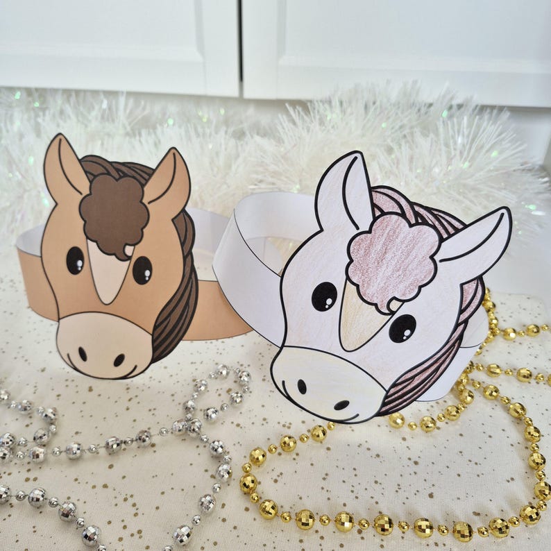 Pu&ograve; includere: Due corone di carta a tema cavallo. Una &egrave; color cuoio con criniera e ciuffo marroni, l'altra &egrave; bianca con criniera rosa e marrone. Le corone sono su una superficie bianca con collane di perline argentate e dorate.