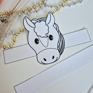 Pu&ograve; includere: Una corona a forma di testa di cavallo in bianco e nero, perfetta per una festa per bambini o un progetto di artigianato. Il viso del cavallo &egrave; dettagliato con grandi occhi e un'espressione amichevole. Due strisce di carta bianca si estendono dalla testa.