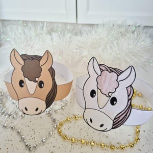 Pu&ograve; includere: Due fasce per la testa a forma di cavallo di carta. Una &egrave; marrone chiaro con una criniera marrone, l'altra &egrave; bianca con una criniera rosa. Entrambe hanno occhi neri e sono su una fascia bianca. Perline decorative e orpelli bianchi sullo sfondo.