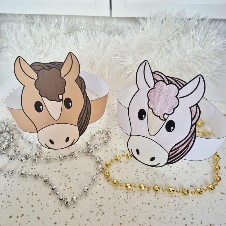 Pu&ograve; includere: Due corone di carta a tema cavallo. Una corona presenta un cavallo marrone con una criniera marrone, mentre l'altra ha un cavallo bianco con una criniera rosa. Entrambe le corone hanno una fascia bianca. Collane di perline argentate e dorate in primo piano.