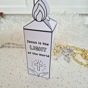 May include: A white paper candle with a flame-shaped top. The candle features the text "Jesus is the LIGHT of the World" with a cross and hands illustration. Decorative beads are in the background.