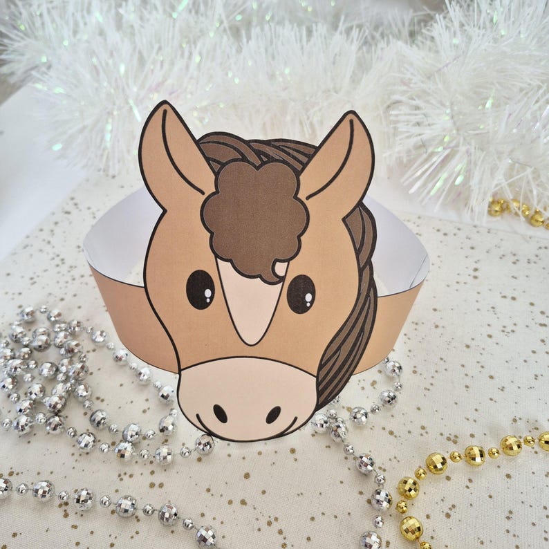 Pu&ograve; includere: Una corona di cavallo di carta con un volto di cavallo dei cartoni animati nei toni del marrone, beige e bianco. La corona &egrave; progettata per essere indossata intorno alla testa. Lo sfondo include perline decorative e orpelli bianchi.